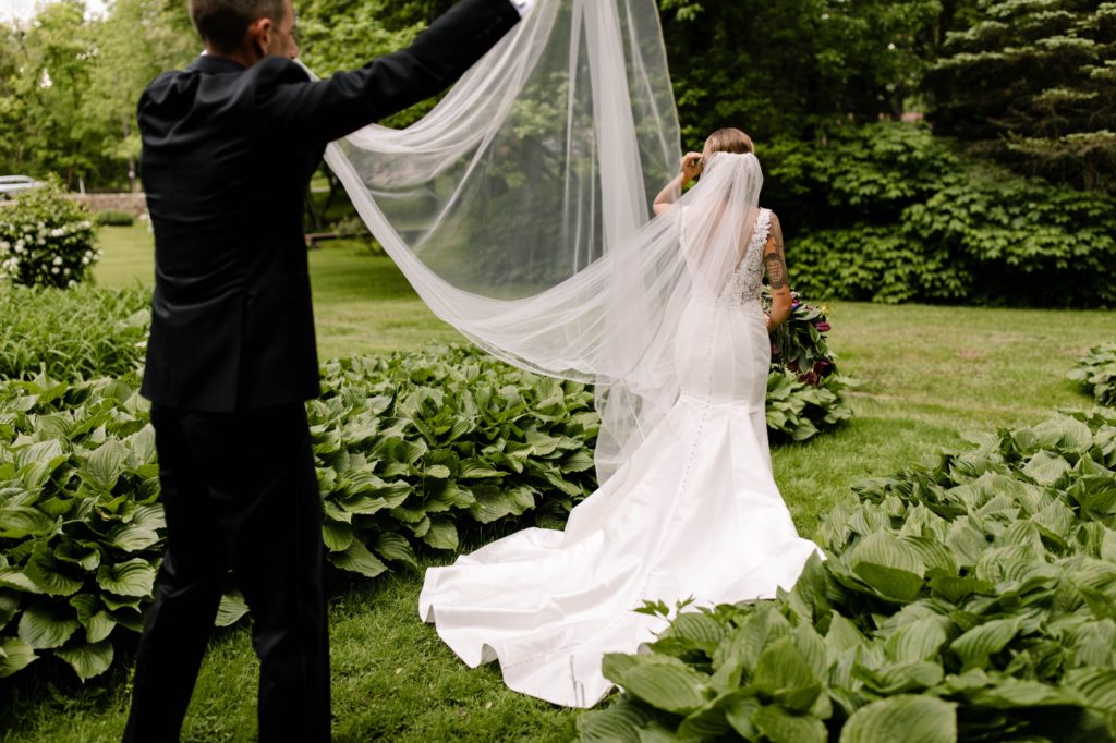 groom holds brides veil