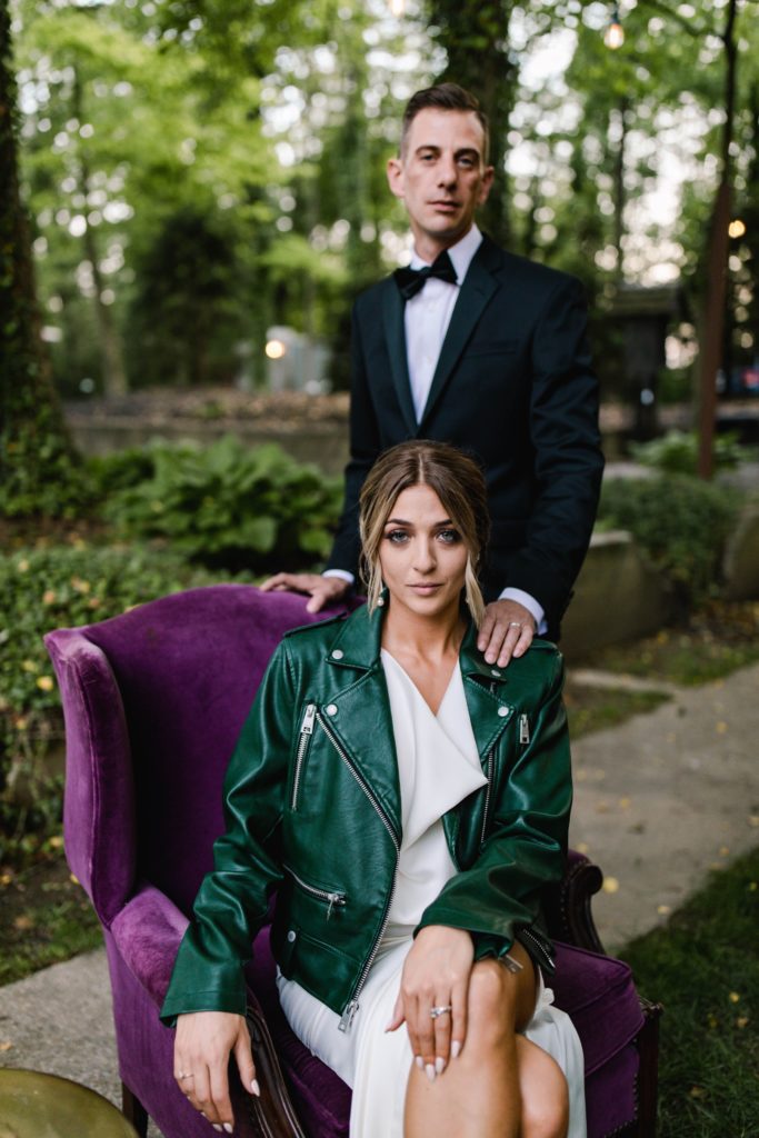bride and groom pose on purple chair