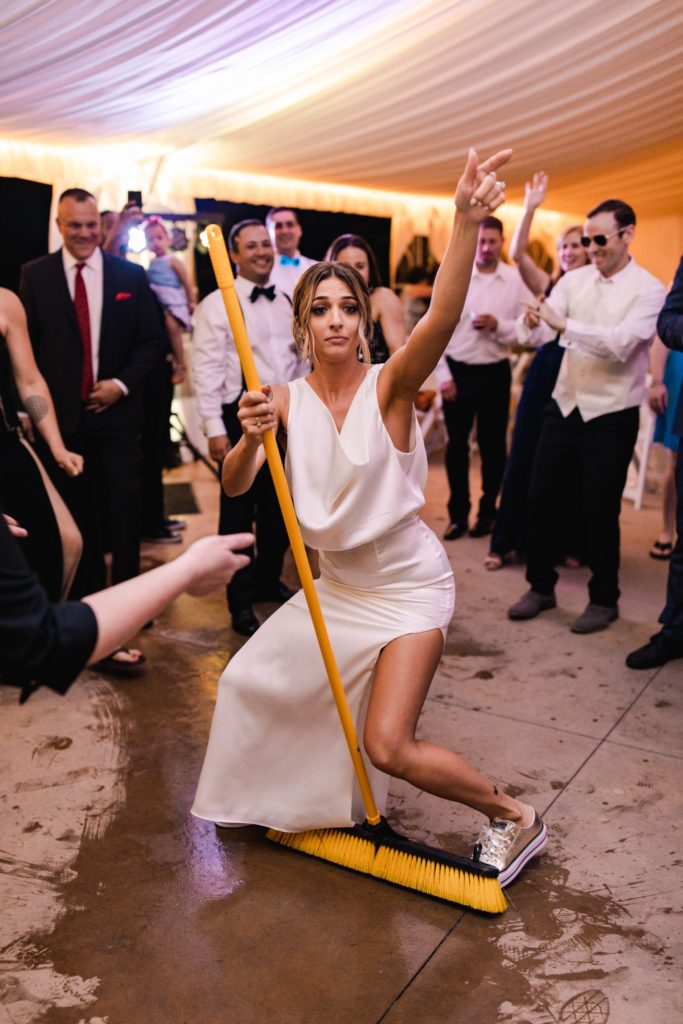 bride dances with broom at wedding reception