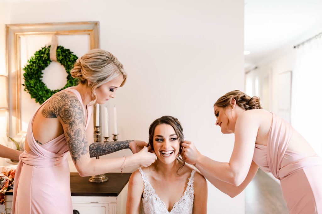 bridesmaids putting on brides earring