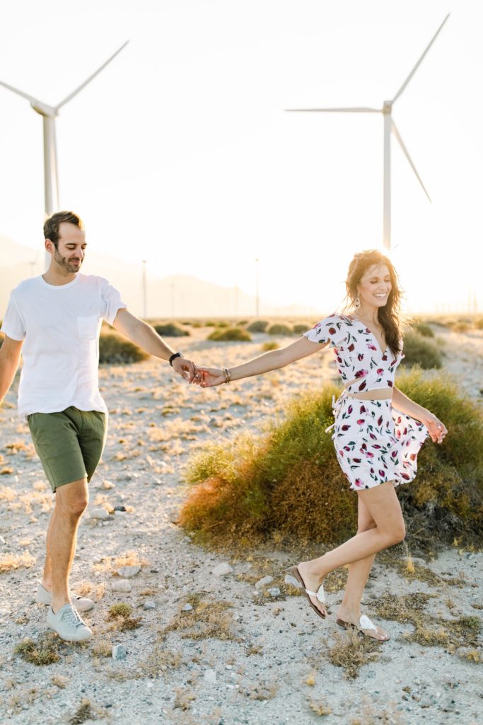 couple running through desert in palm springs for engagement session