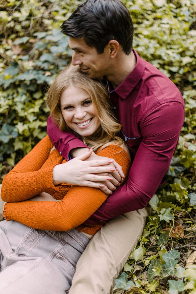 couple sitting in ivy for engagement session 