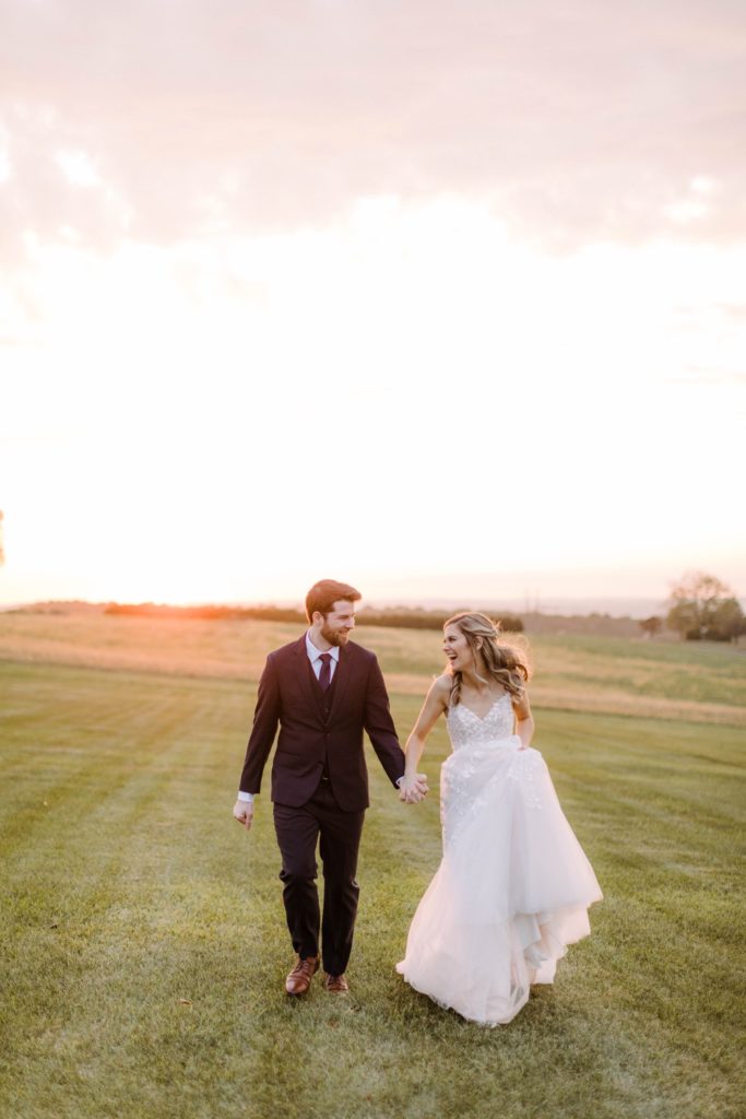 bride and groom run into sunset 