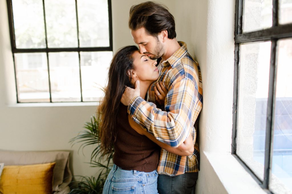 couple kissing against wall during in home session