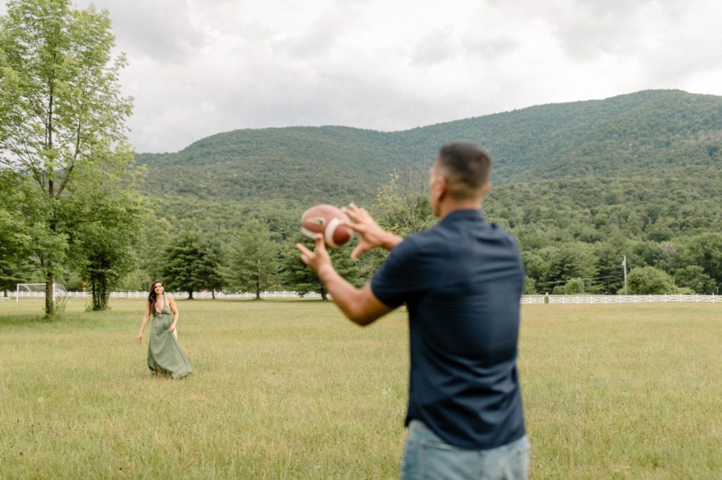 couple playing football in field in woodstock