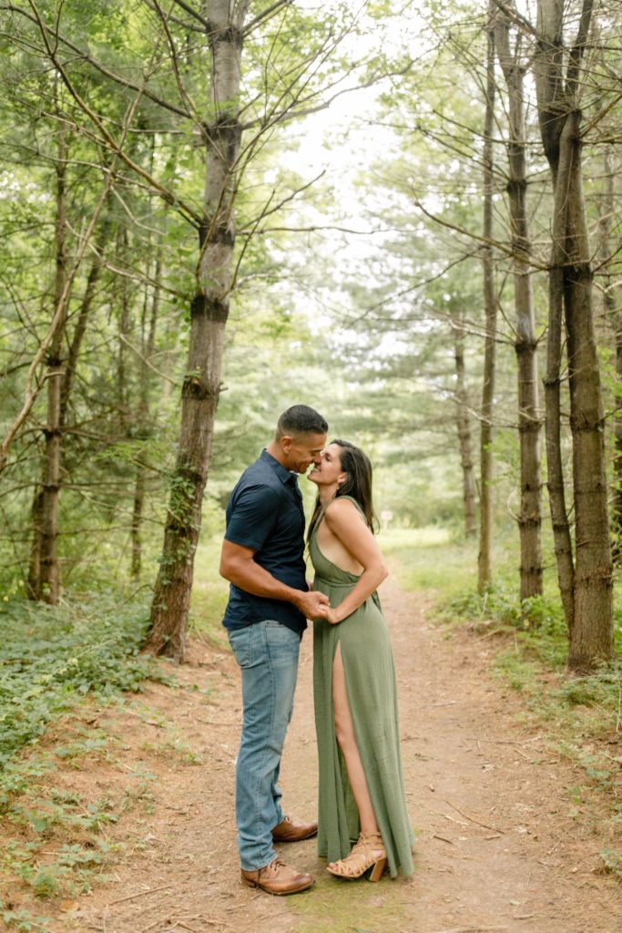 couple kissing in pine trees for woodstock engagement session