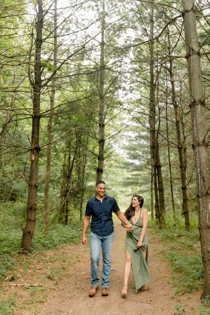 couple walking through a pine tree forest