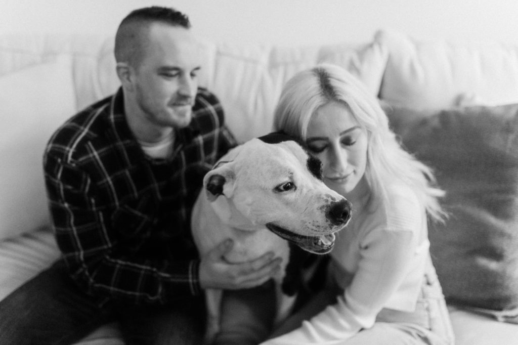 a couple hugging their dog at in home engagement session