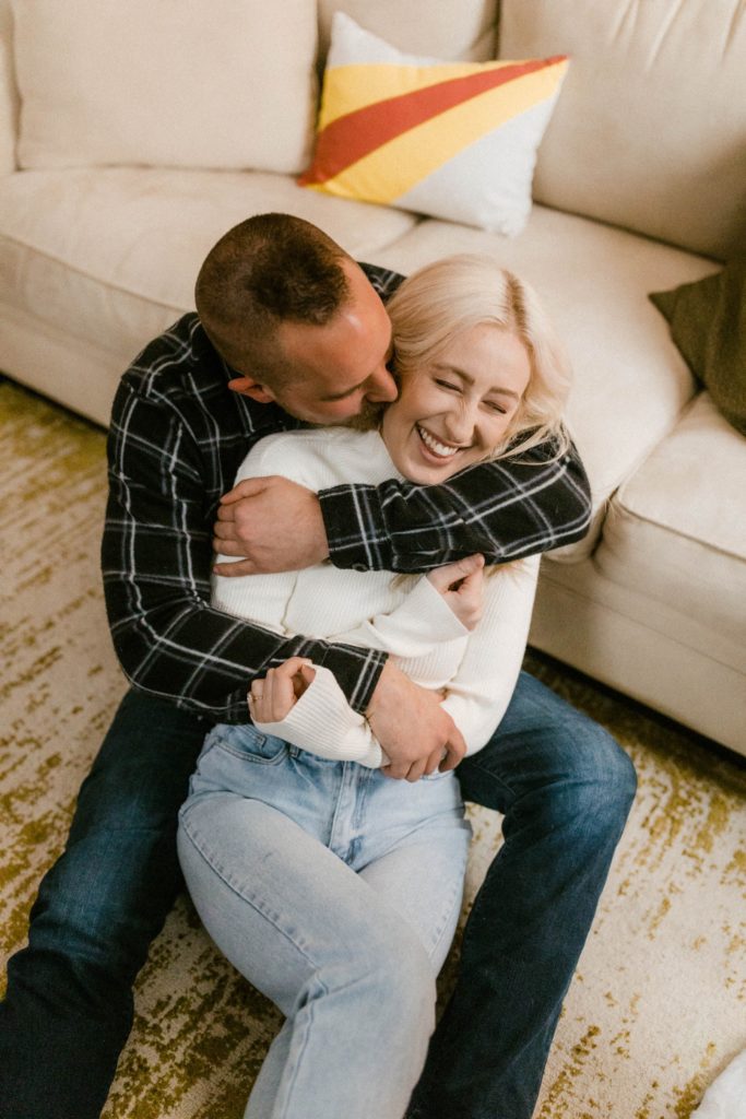 couple snuggling and hugging for in home engagement session 