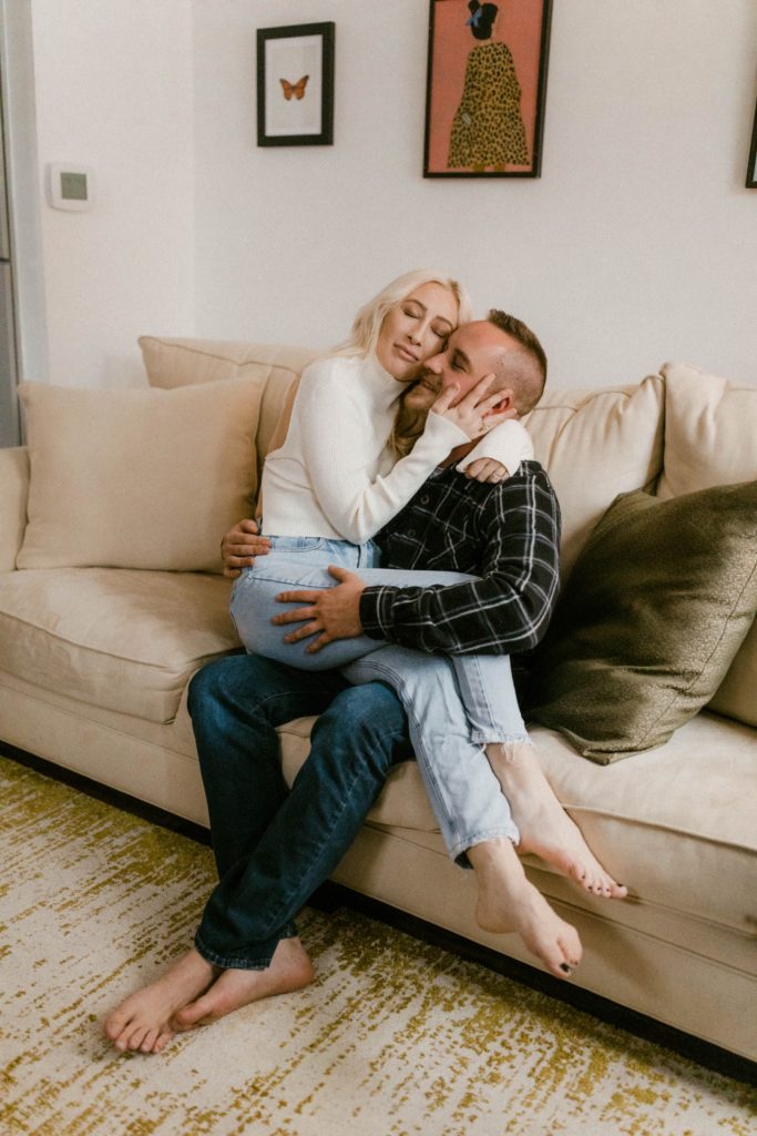 a couple snuggling on couch for in home engagement session 