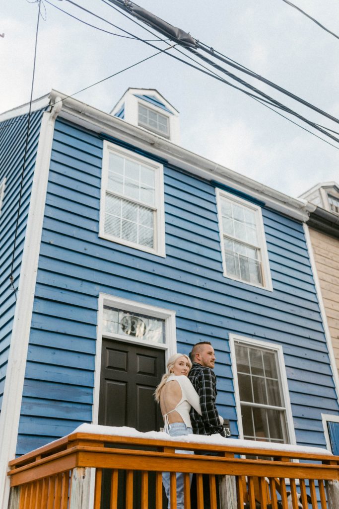 a girl hugs a guy in front of home for engagement session 