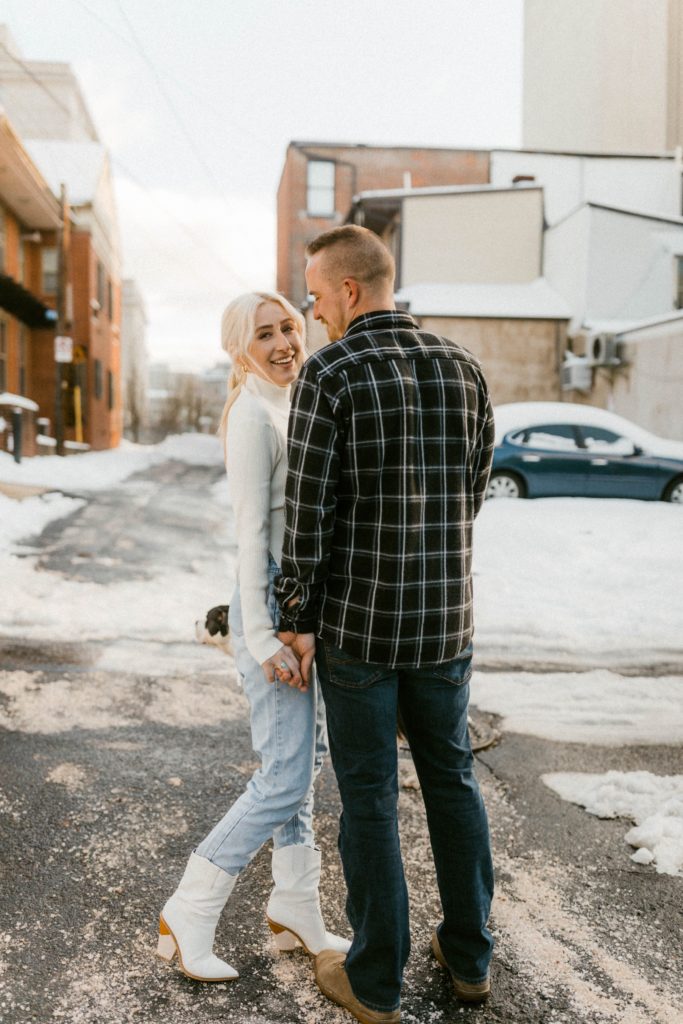 a couple snuggling on snow covered street for engagement session 