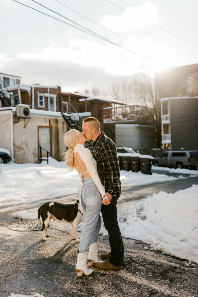 a couple kiss on snow covered street for winter engagement session 