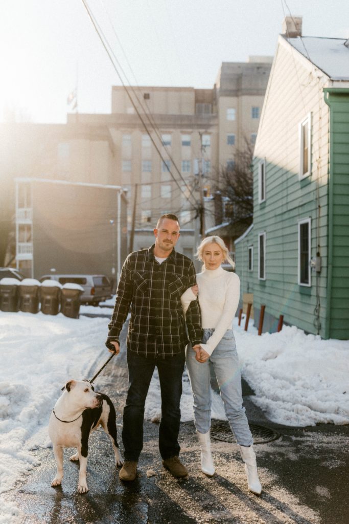 a couple pose on a snow covered street for engagement session 