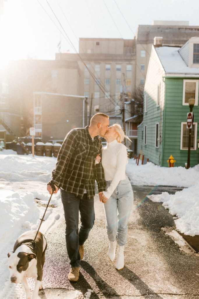 a couple walks and kisses on snow covered street 