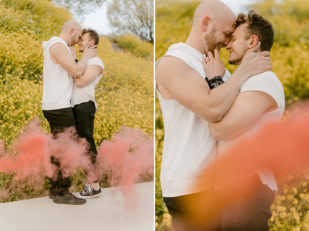 a couple laughing and kissing holding smoke bombs