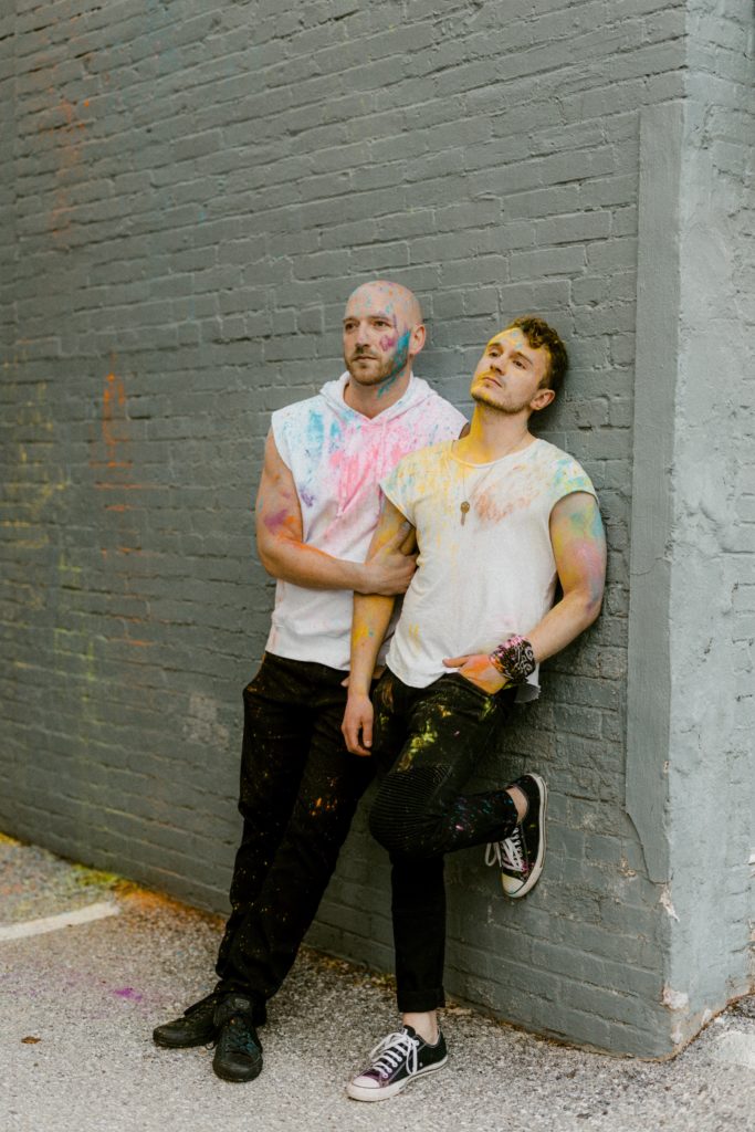 a couple poses on a wall covered in paint