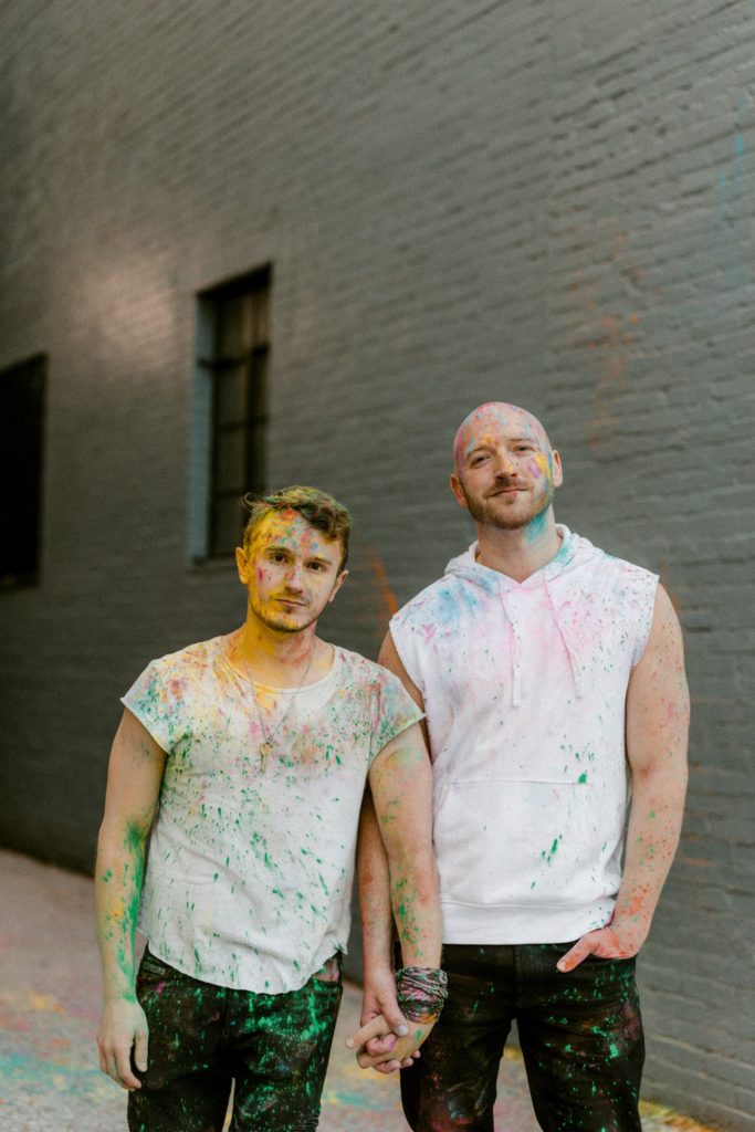a couple poses for a session while covered in paint