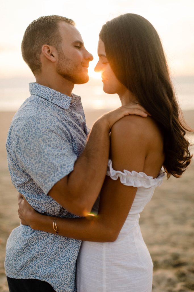 couple snuggling in closely on beach for sunrise rehoboth beach engagement session