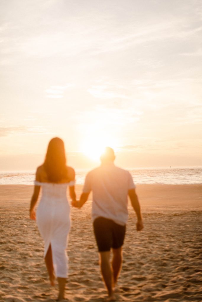 couple walking off into sunrise on beach for sunrise rehoboth beach engagement session