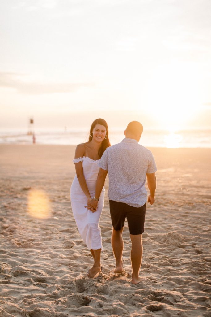 couple laughing on beach at sunrise 