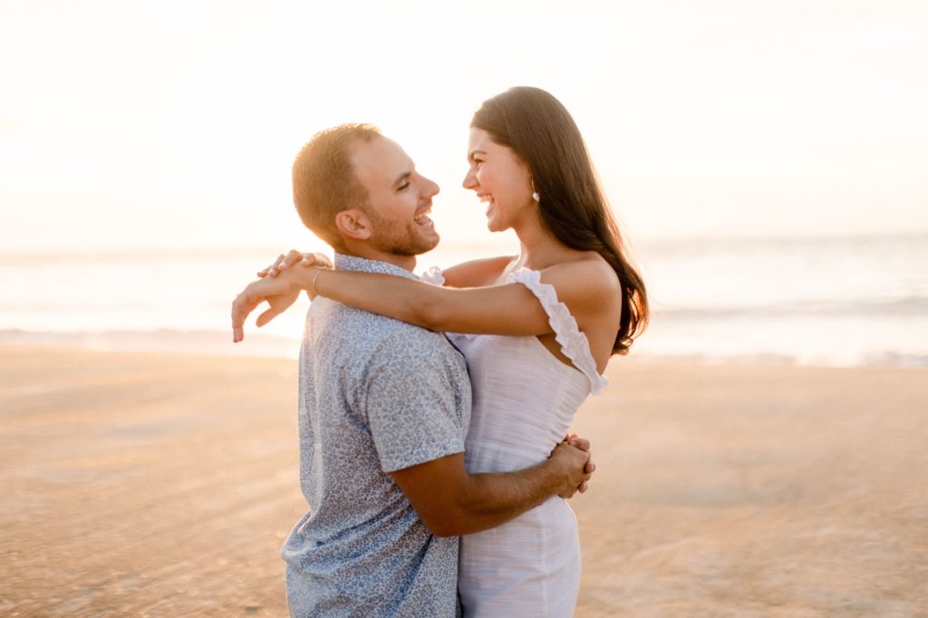 couple snuggling on beach for engagement session 