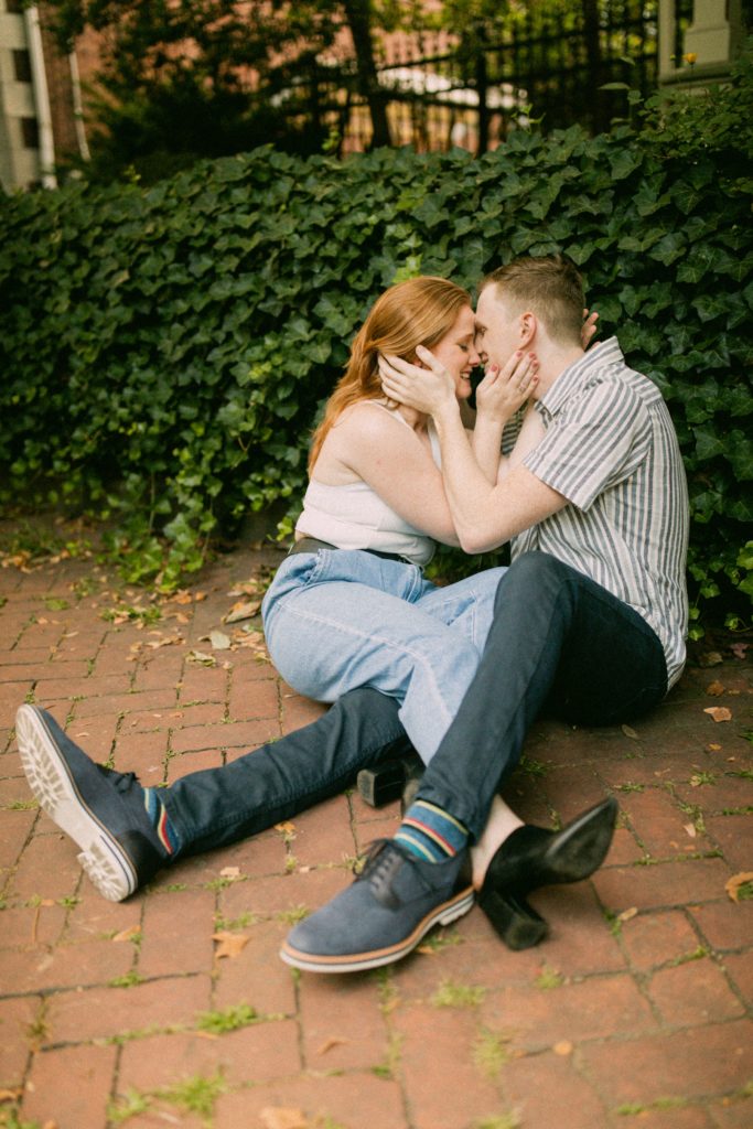 couple sitting and kissing on sidewalk for romantic philadelphia couples session