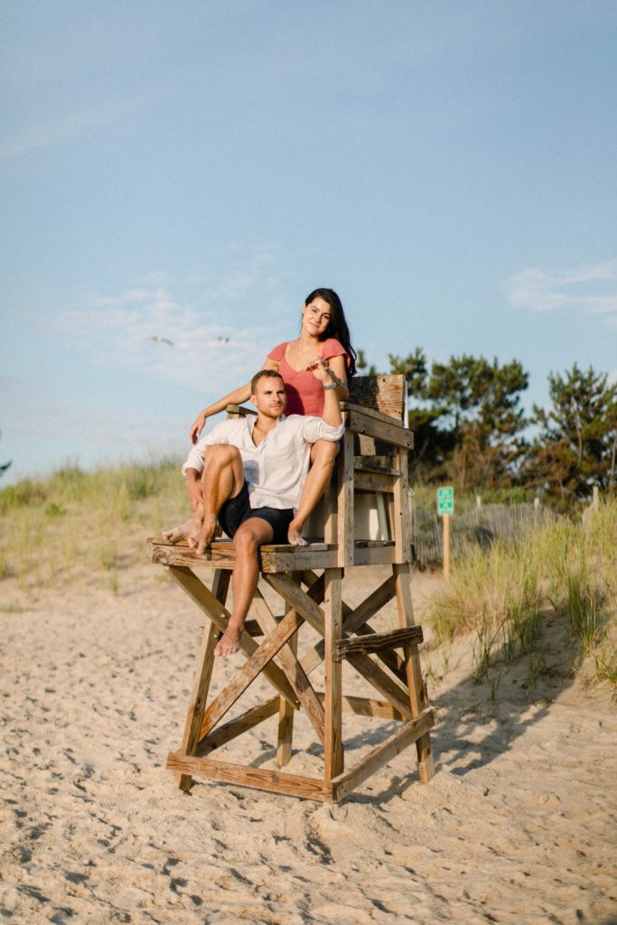 a couple posing on lifeguard chair for engagement session 