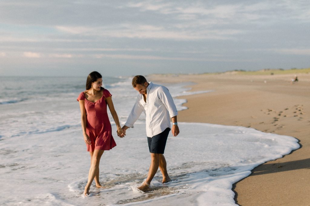 couple walking along beach for engagement session 