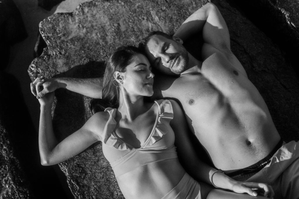 a couple laying on rocks in bathing suit 