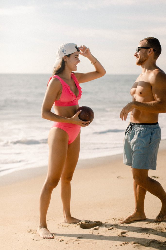a couple plays football on the beach 
