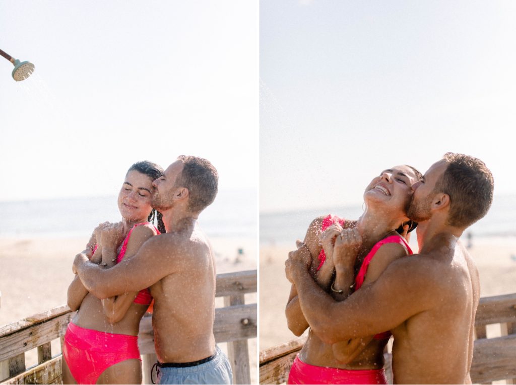 couple snuggles under beach shower for sunrise rehoboth beach engagement session