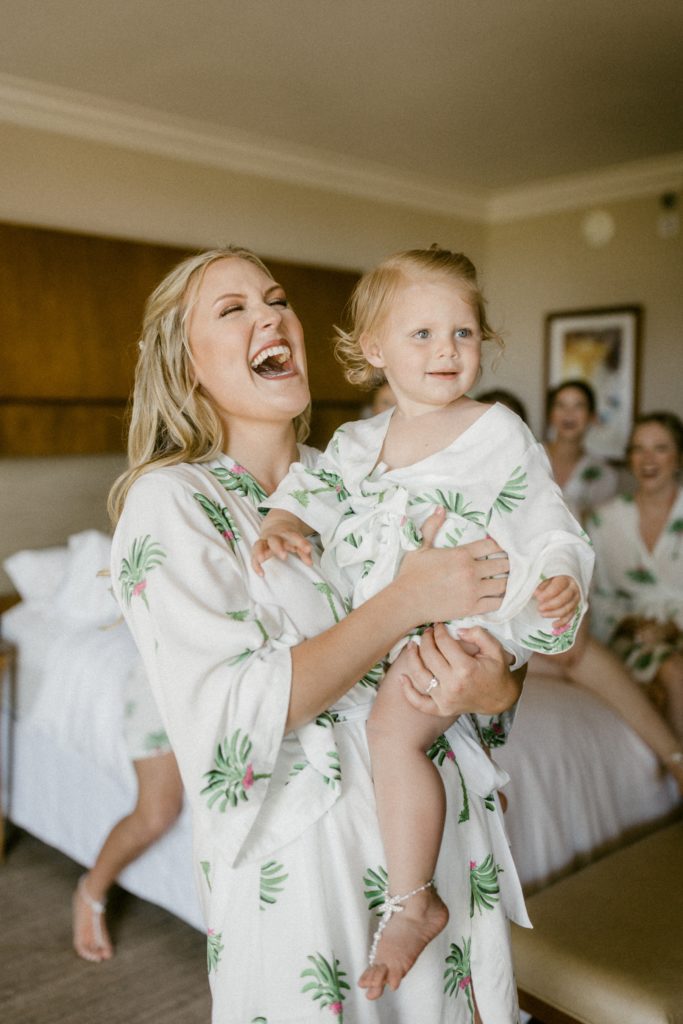 bride holding niece laughing at wedding photos 