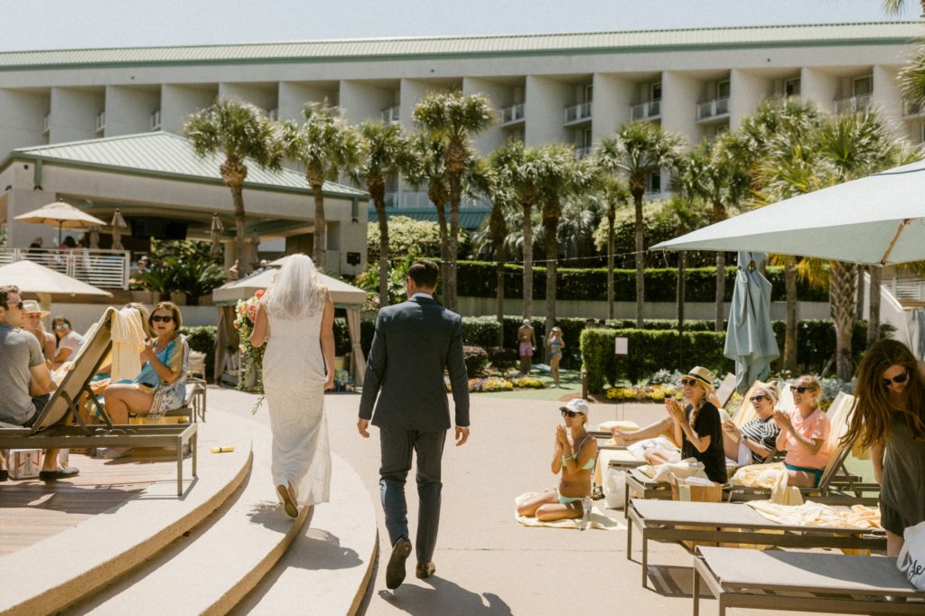 bride and groom walk by pool 