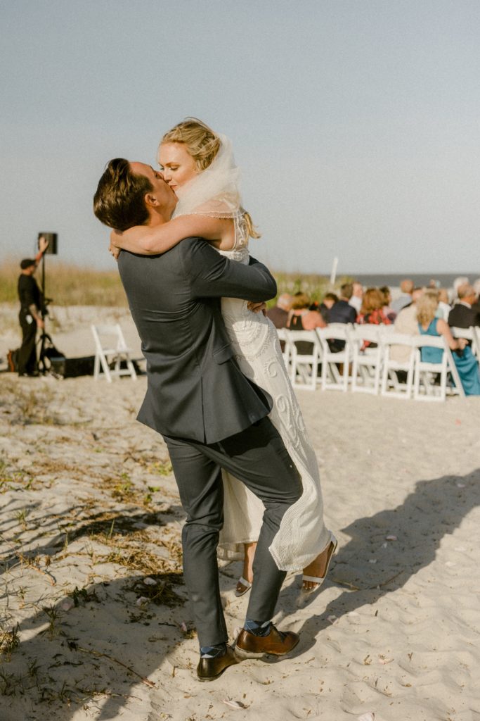 groom picks up bride to kiss at end of isle 
