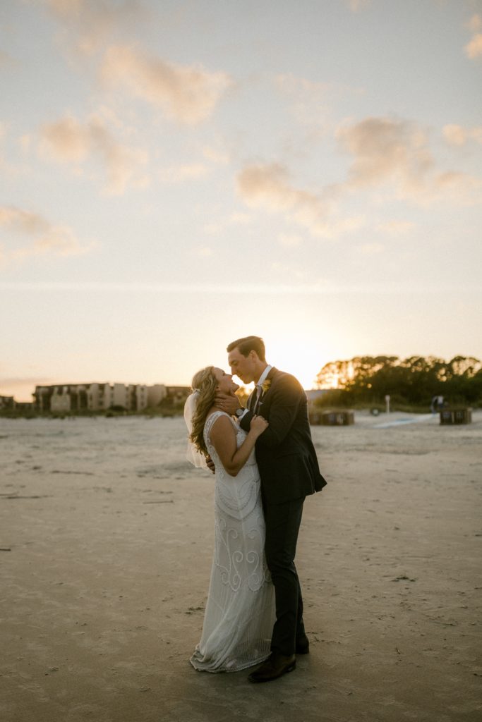 bride and groom kiss in front of the sunset for wedding photos 