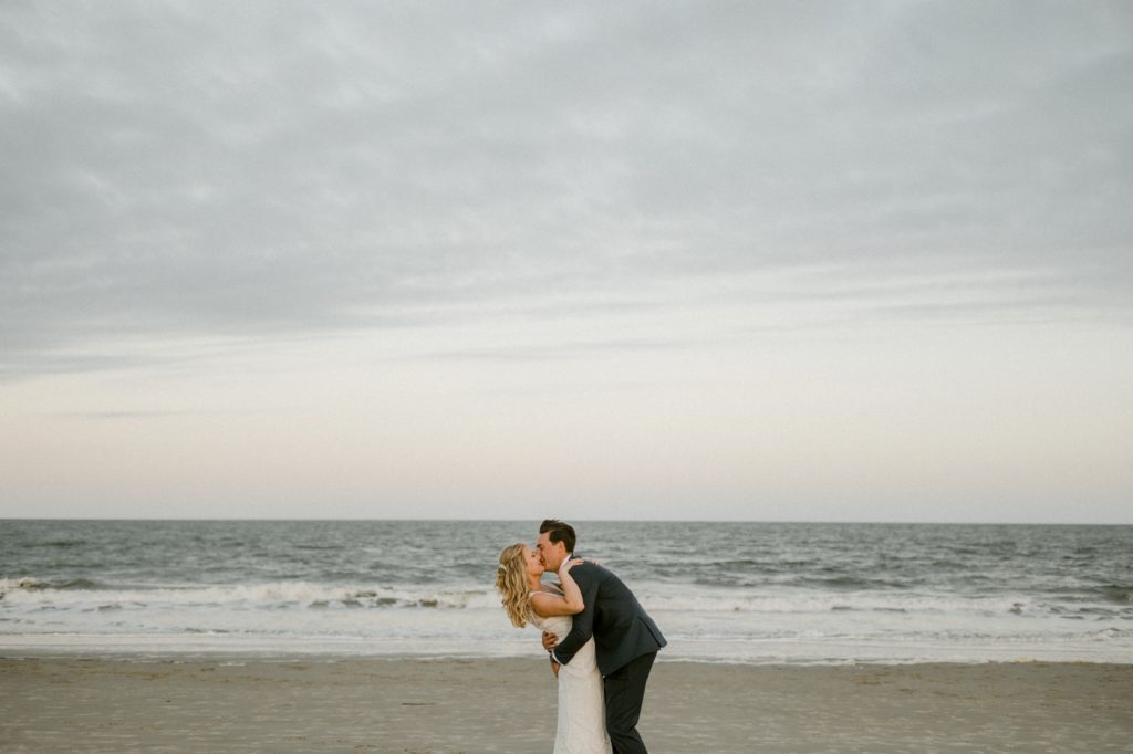bride and groom kiss at sunset on beach for hilton head beach wedding 