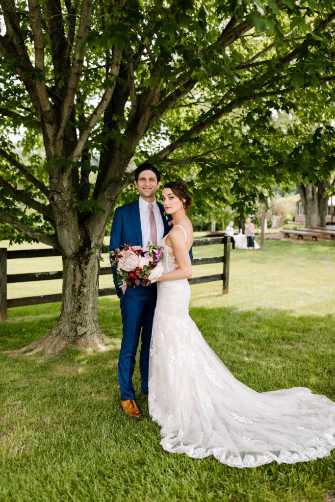 bride and groom posing under tree