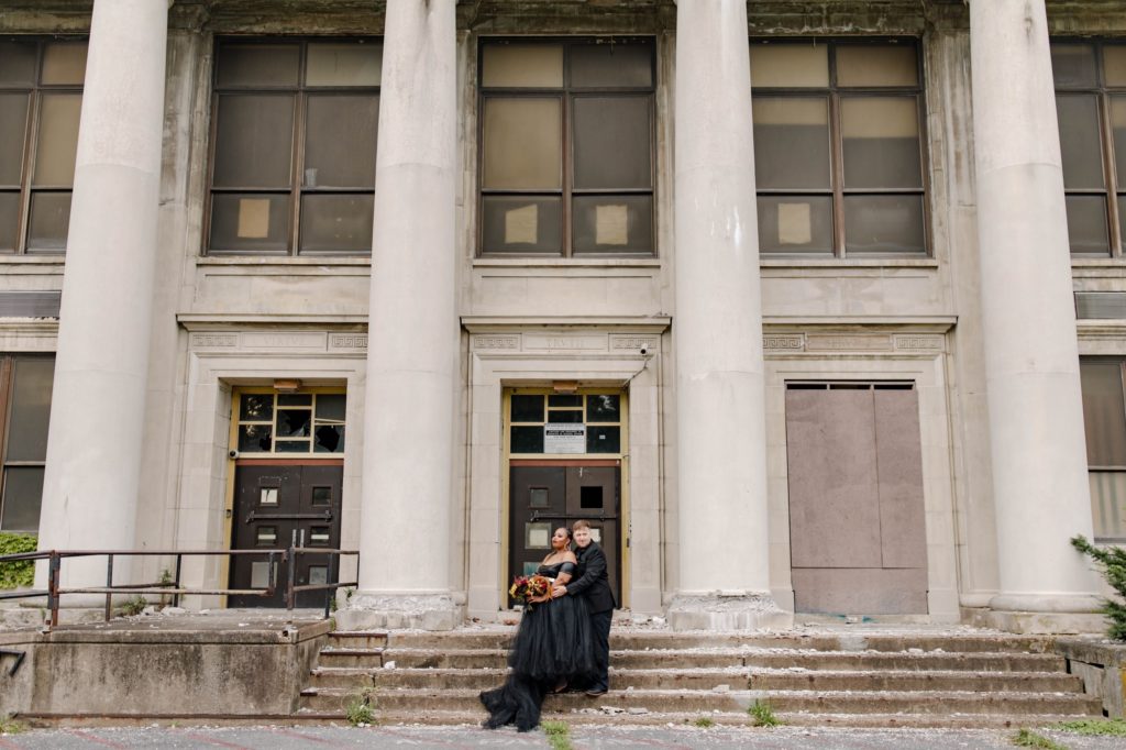 couple posing for anniversary session in front of abandoned building