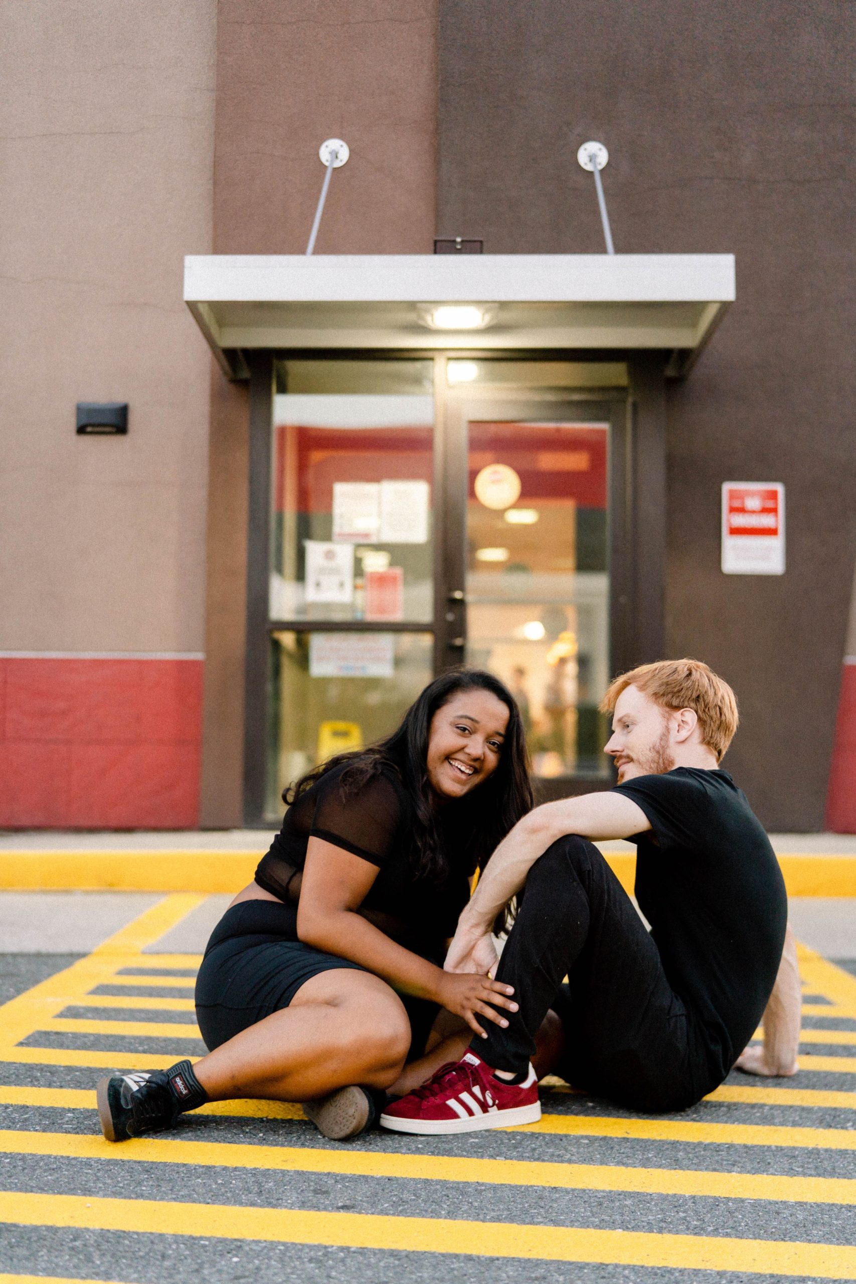 couple posing for photos on ground at truck stop