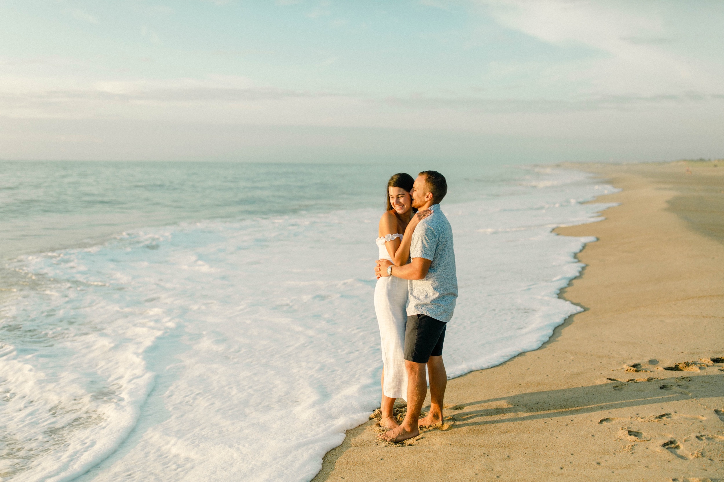 couple snuggle by the ocean for sunrise rehoboth beach engagement session