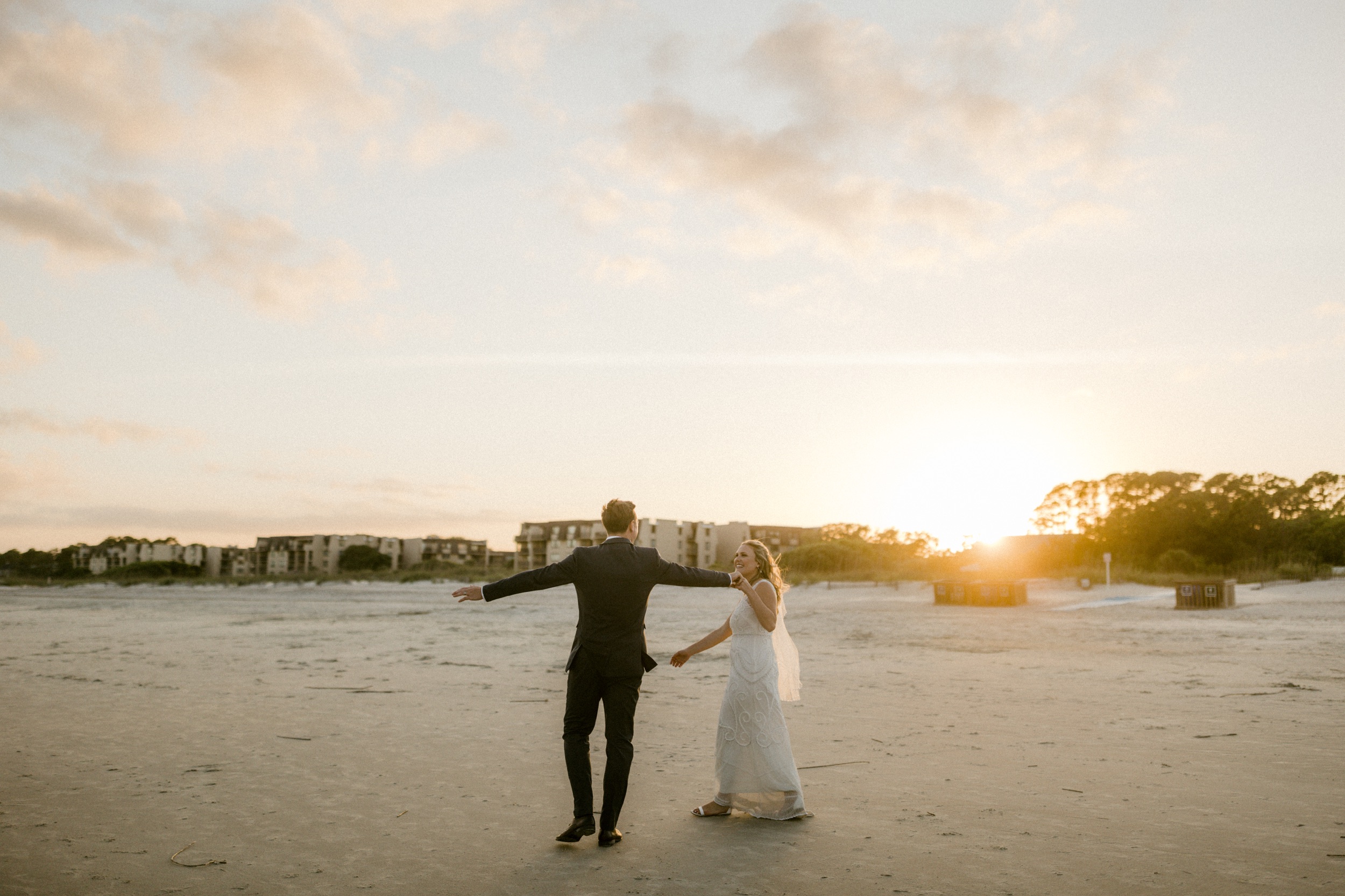 bride and groom walk along beach for wedding photos at hilton head beach wedding