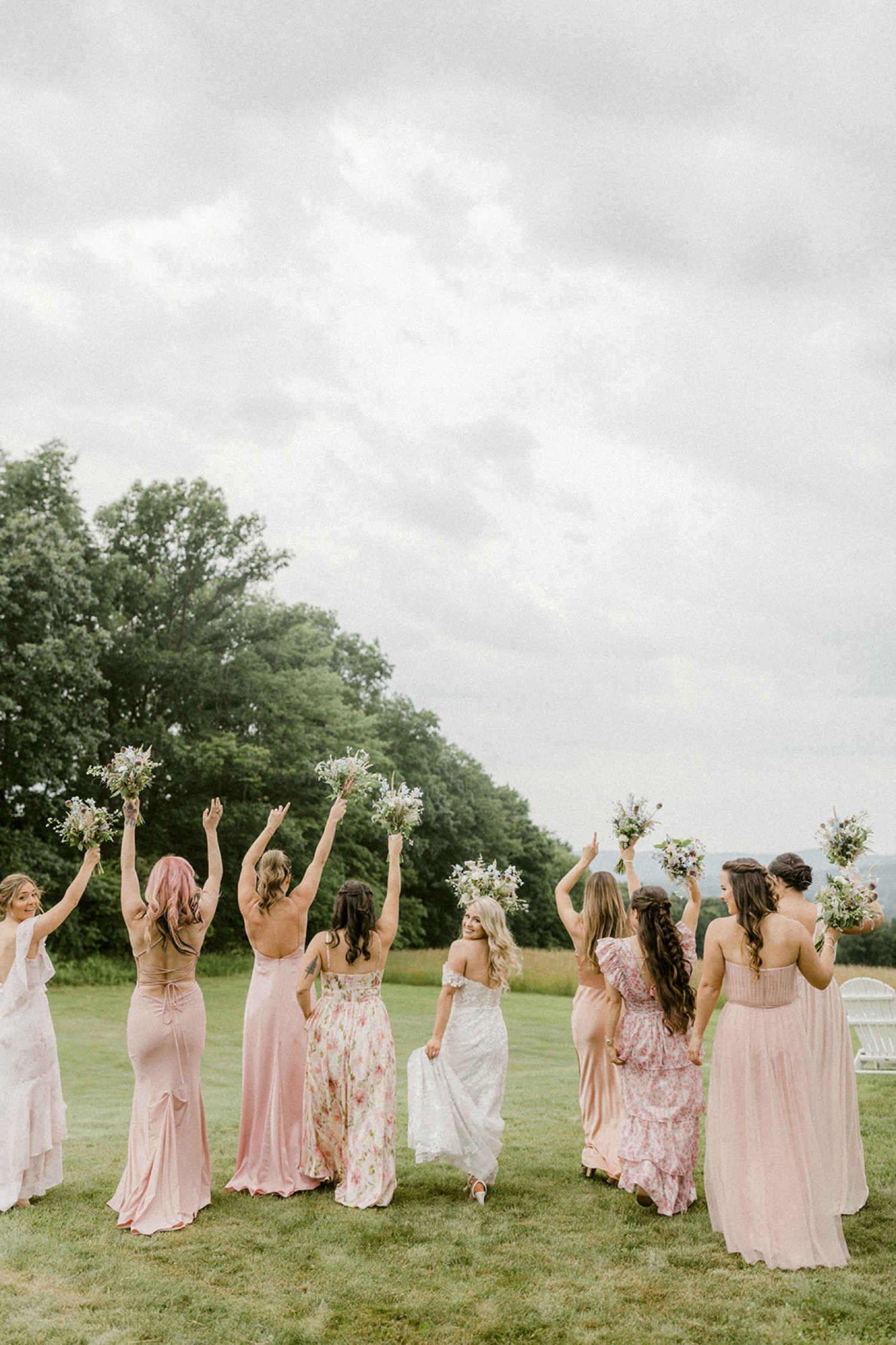 bridesmaids running in field bouquets pink dresses