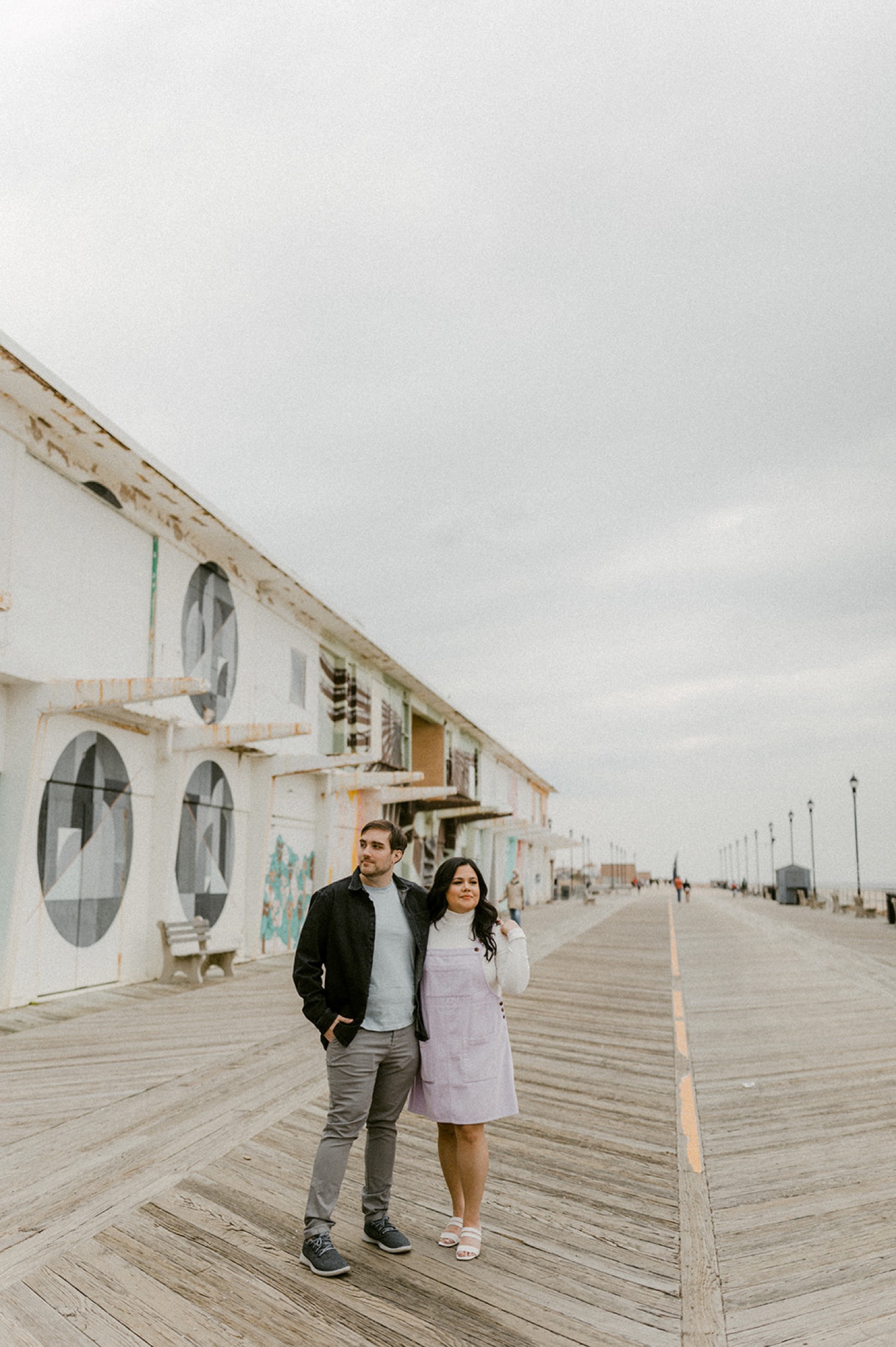 couple on boardwalk with colorful murals in the background