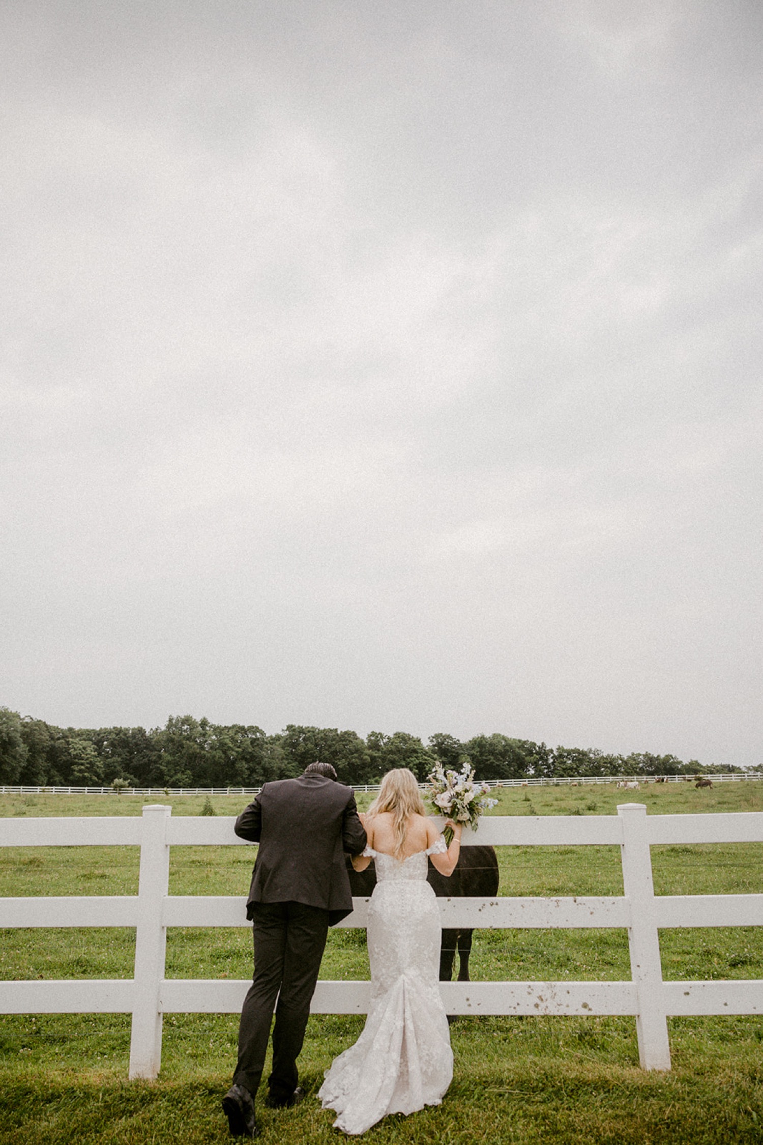 couple looking over white fence at farm animals