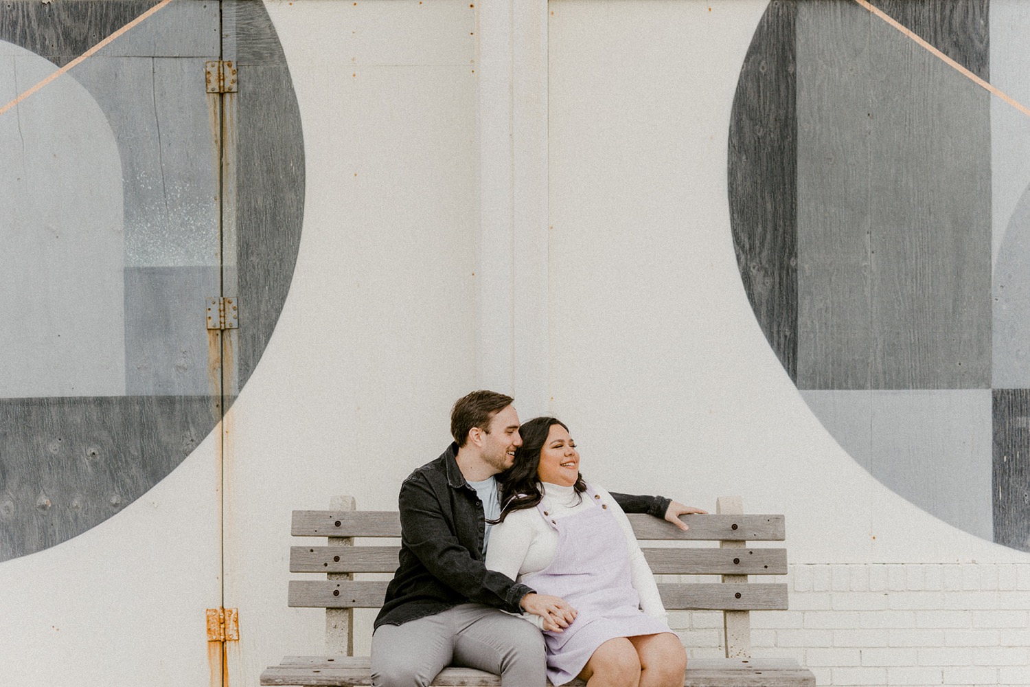 couple sitting on bench with abstract mural in background