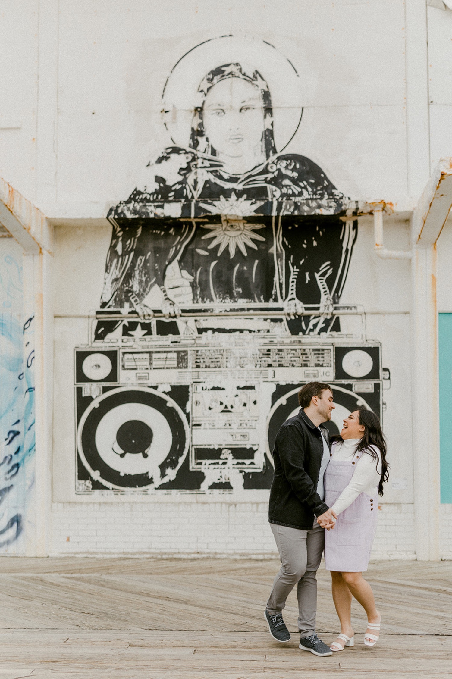 couple holding hands in front of stereo mural