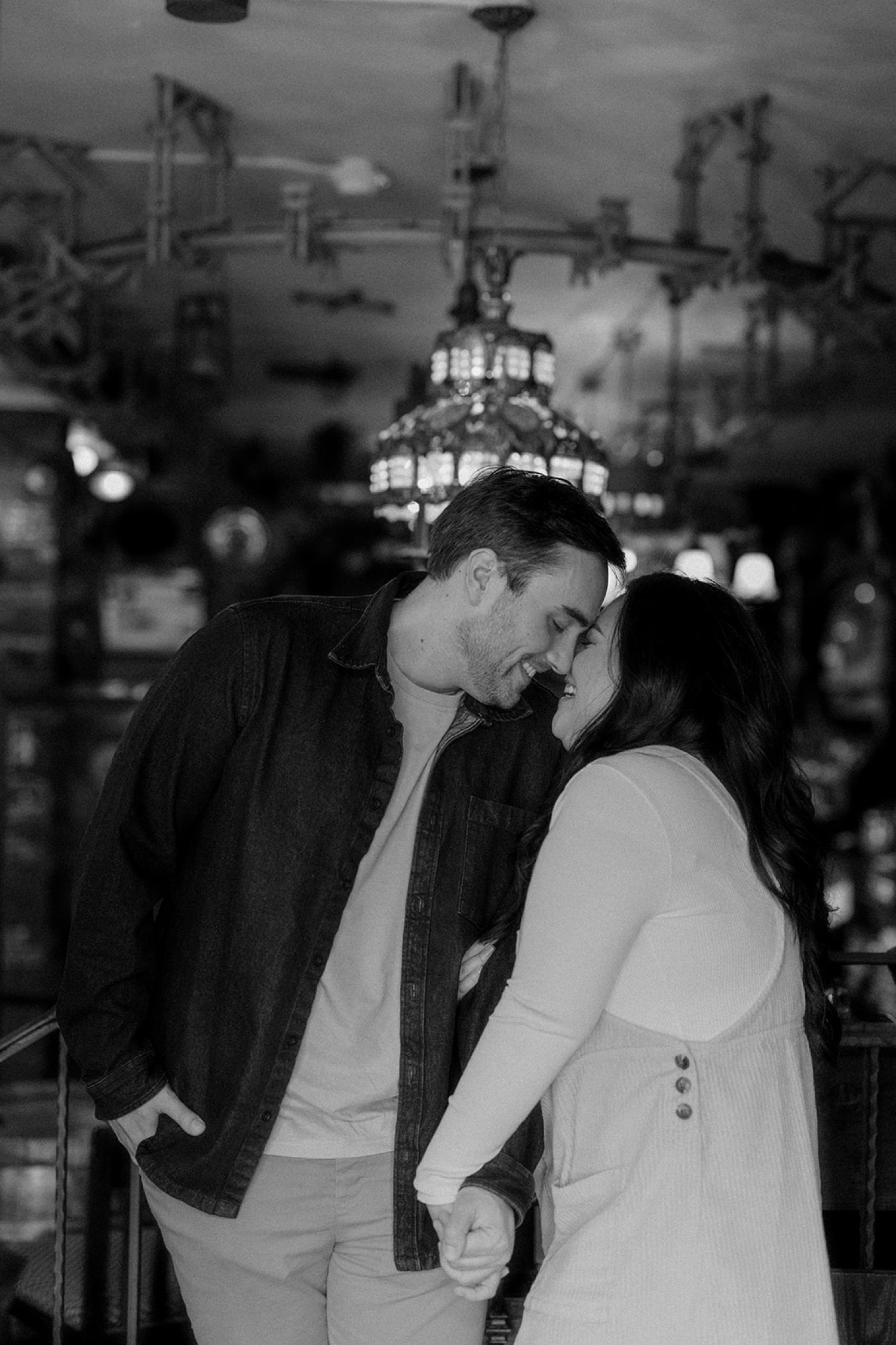 couple nose kiss in front of antique light fixtures