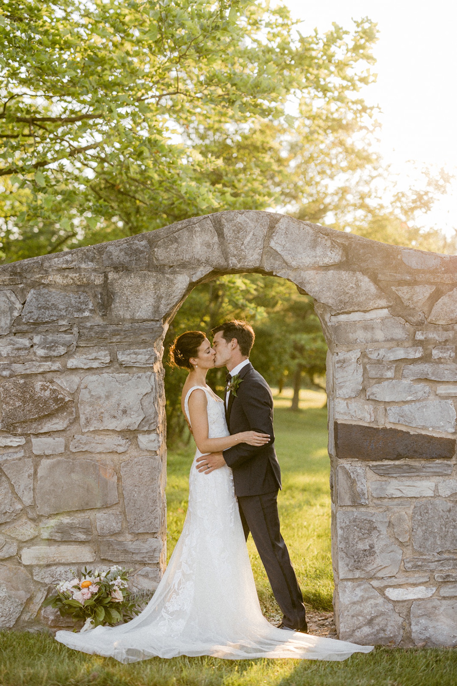 couple kissing under stone archway outdoor wedding portraits