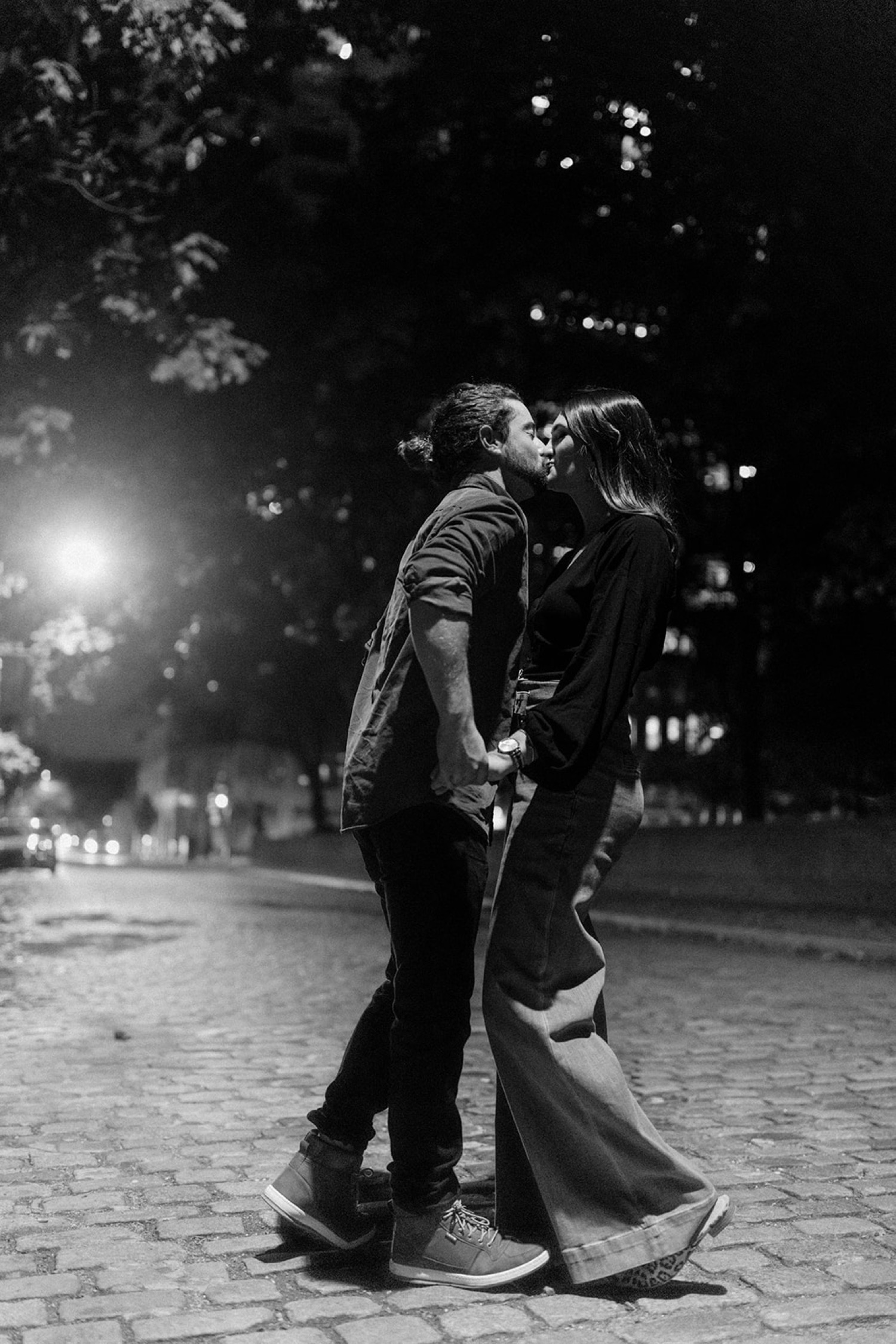 couple kissing on cobblestone street at night